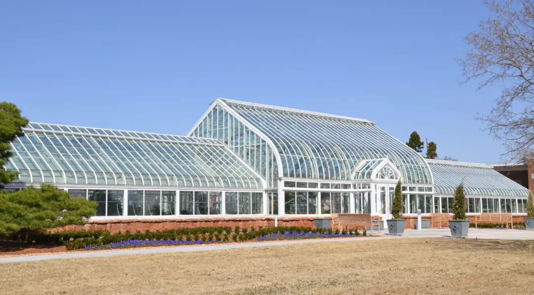 A large greenhouse with many windows and plants.